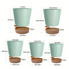 A set of five light mint green self-watering plant pots with drainage holes shown in various sizes.