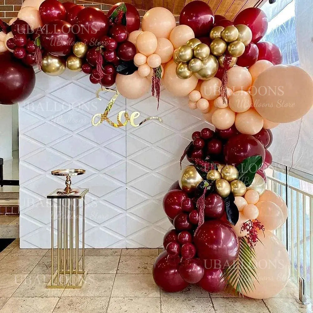 A large arrangement of deep burgundy and peach latex balloons for parties and events