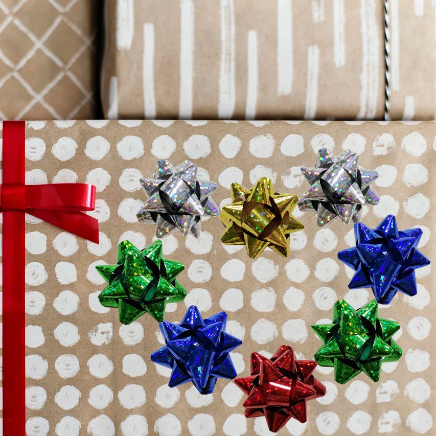 A collection of six holographic star gift bows in various colors arranged in a circle on brown paper.