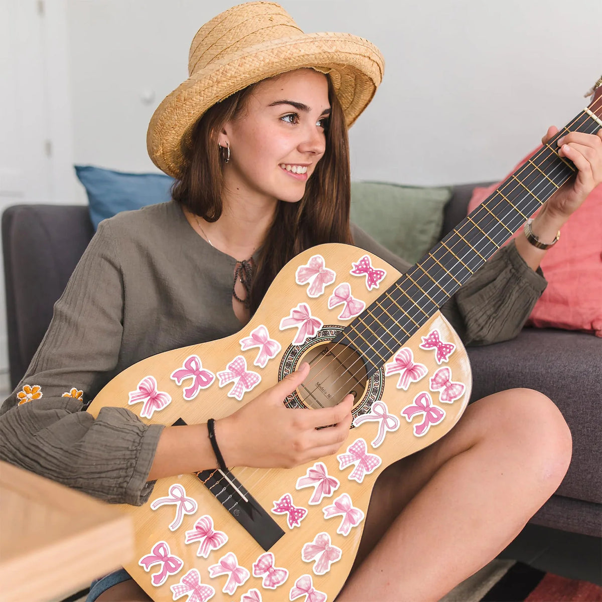 A young woman plays a light yellow acoustic guitar decorated with pink butterfly stickers.