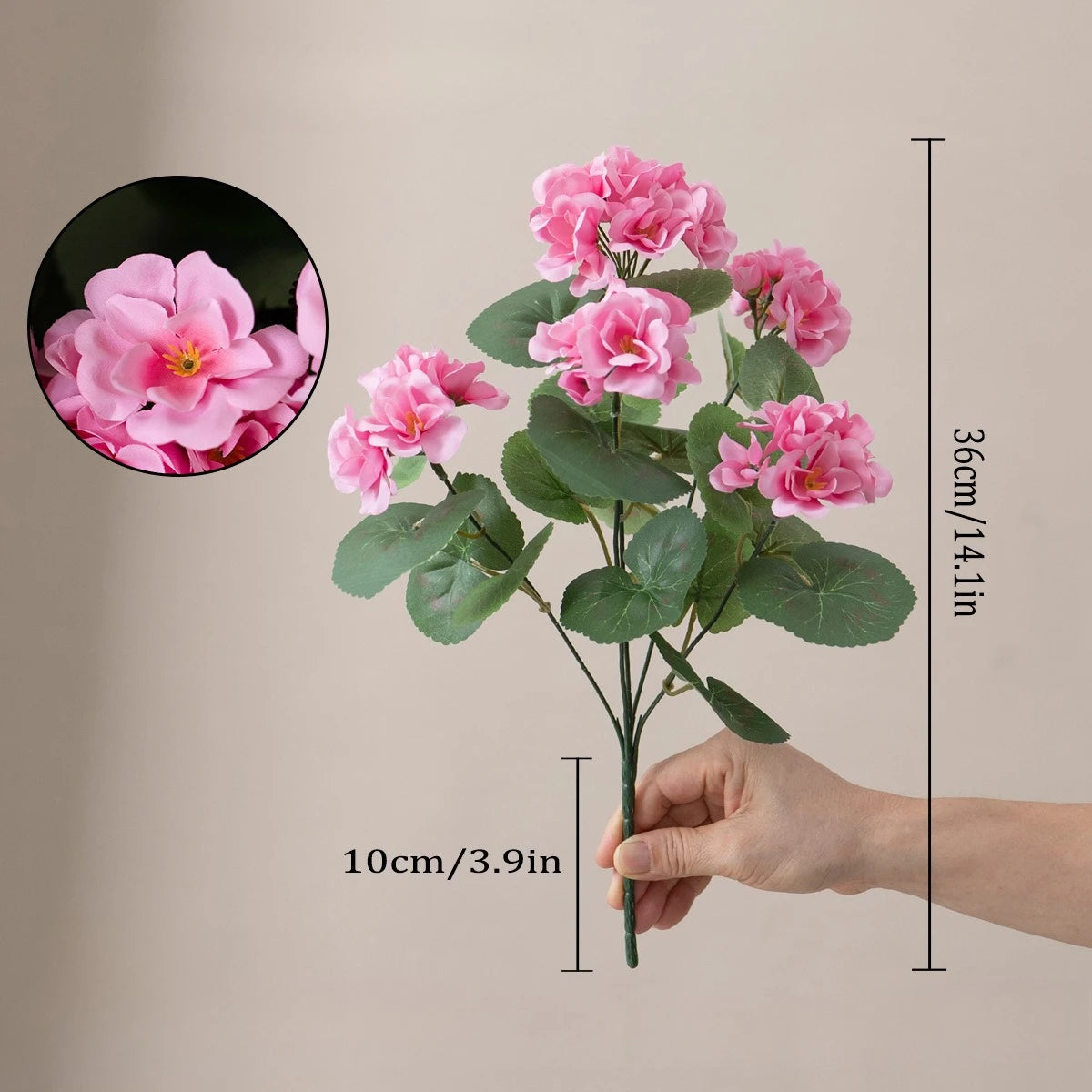 Una mano sostiene un tallo de flores artificiales de geranio rosa de seda con hojas, mostrado junto a una vista ampliada.