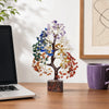 A bendable crystal tree ornament with multicolored leaves displayed on a wooden desk.