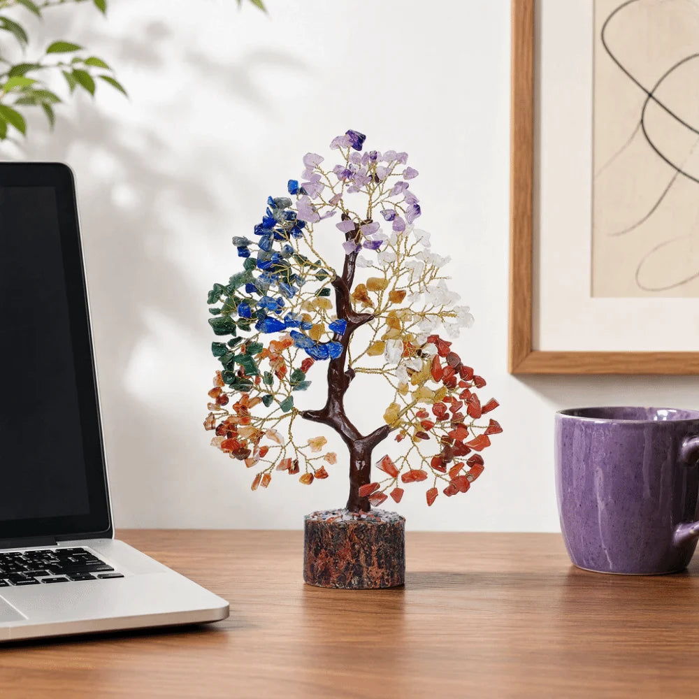 A bendable crystal tree ornament with multicolored leaves displayed on a wooden desk.