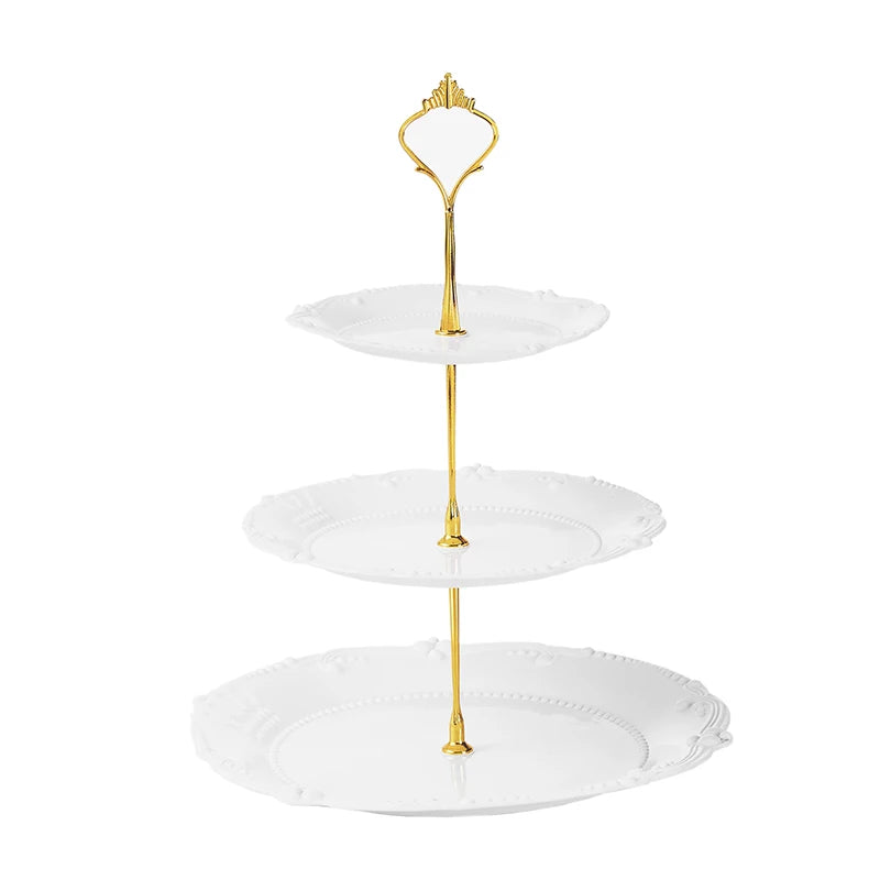 A gold-colored three-tier plastic cupcake stand with white plates and a decorative golden fork.
