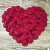 A heart-shaped arrangement of deep red silk rose petals for weddings and events.