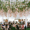 An outdoor wedding setup featuring a pink rose pearl leaf garland ribbon hanging from a white tent structure.