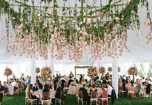 An outdoor wedding setup featuring a pink rose pearl leaf garland ribbon hanging from a white tent structure.