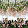 An outdoor wedding ceremony setup featuring a pink rose pearl leaf garland draped across the ceiling.
