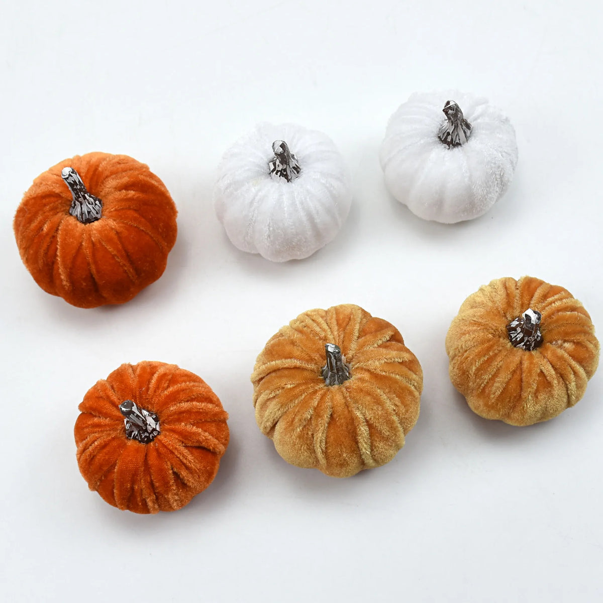 A set of ten velvet pumpkin decorations in shades of orange and white with silver accents.