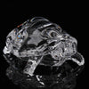 A clear glass miniature tortoise statue reflecting on a dark surface.