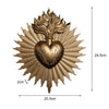 A brass wall plaque featuring a radiant sunburst design surrounding a heart shape.