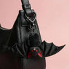 A black faux leather handbag with a bat-themed charm attached to the strap.