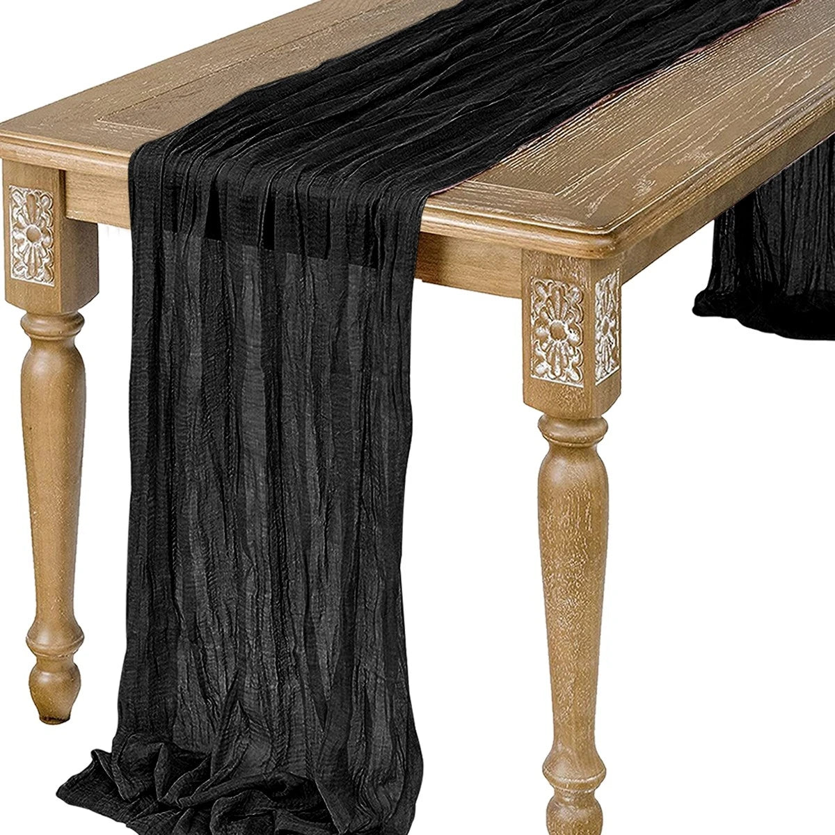 Black semi-sheer gauze table runner draped over a wooden table.