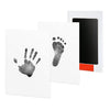 A white card featuring a handprint and footprint impression, next to a black photo frame.