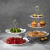 A gold-colored three-tier detachable cake stand holding various desserts and fresh fruit.