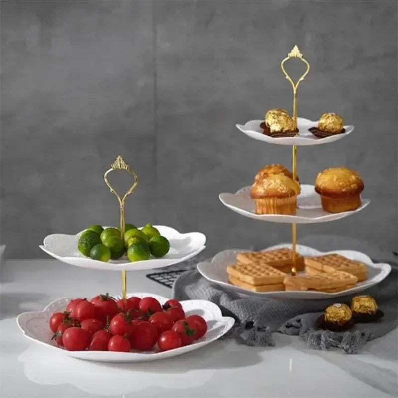 A gold-colored three-tier detachable cake stand holding various desserts and fresh fruit.