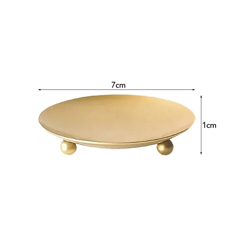 A round, shallow tray or holder with a gold finish and small gold accents, measuring 7cm in diameter.