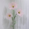 A large artificial silk pink poppy flower displayed on a green stand against a white background.