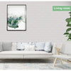 A living room interior featuring a sofa with light cushions and a framed watercolor painting of misty green landscape.