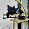 A black cat sits on a wooden sign that reads Coffee Time with a steaming cup design.