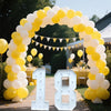 A large archway made of yellow and white balloons framing a path with light-up marquee numbers 18.