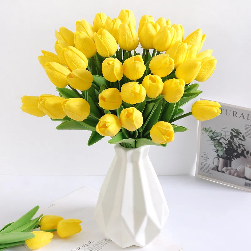 A bouquet of bright yellow artificial tulip flowers in a white vase