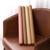 A set of five cylindrical self-adhesive PU leather furniture repair patches in various neutral tones are displayed on a brown