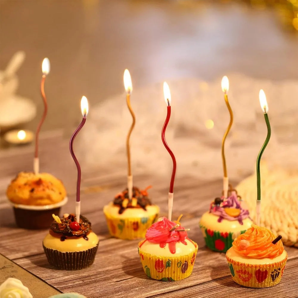 A collection of rainbow birthday candles in various colors and shapes displayed on a wooden surface.