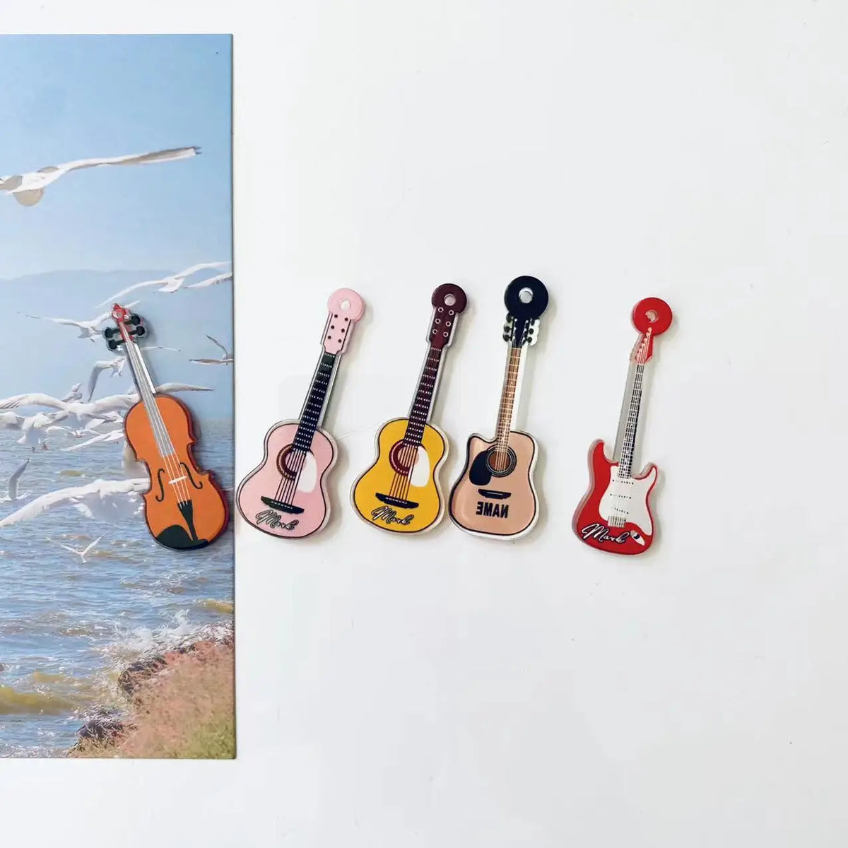 A set of five guitar-shaped fridge magnets in various colors and finishes.