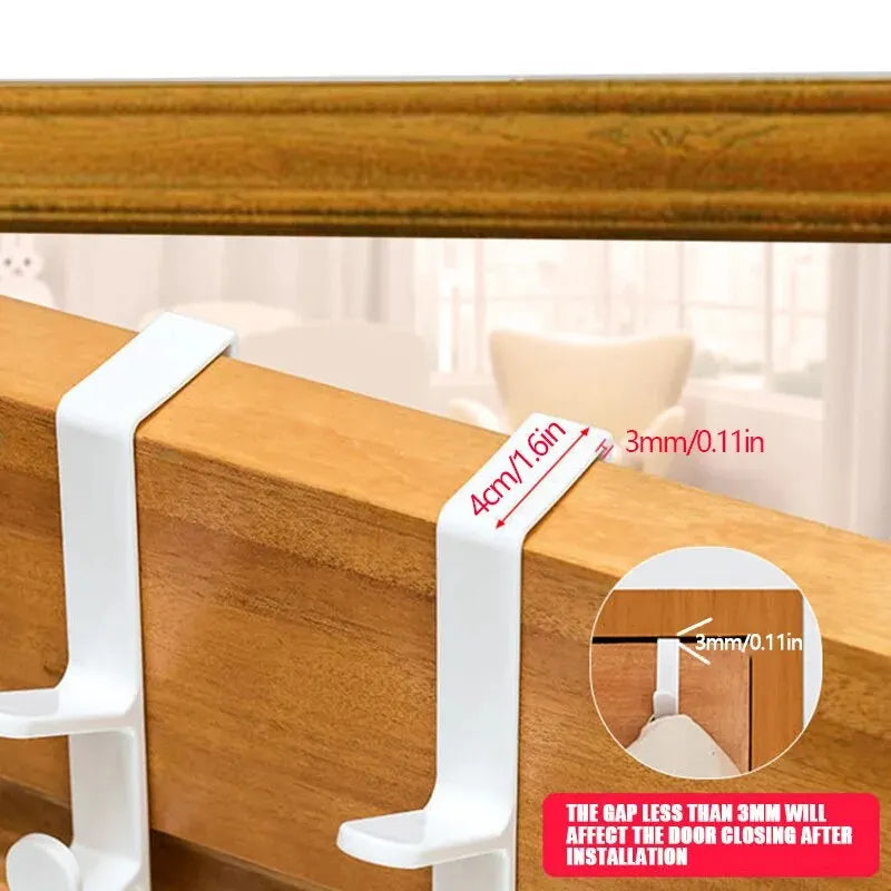 White over-the-door hooks installed on a wooden door frame, demonstrating proper placement for bags and hats.