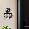 A black iron skull wall hook with a floral accent displaying various hanging items.