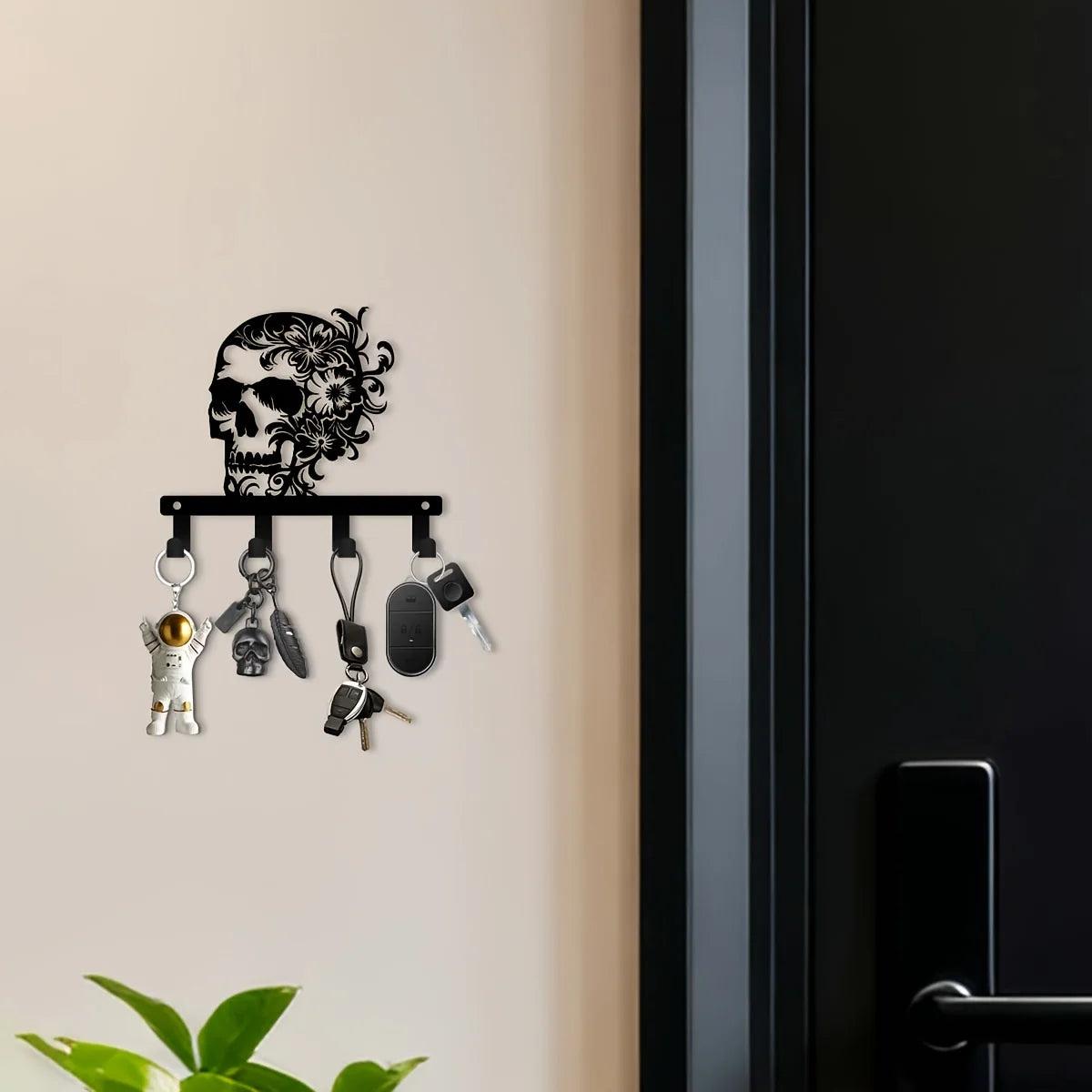 A black iron skull wall hook with a floral accent displaying various hanging items.