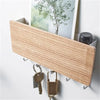 A light wood bamboo wall-mounted key rack with six hooks is displayed against a white wall.