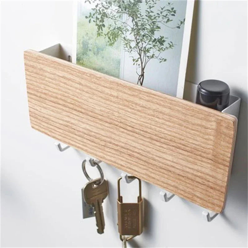 A light wood bamboo wall-mounted key rack with six hooks is displayed against a white wall.