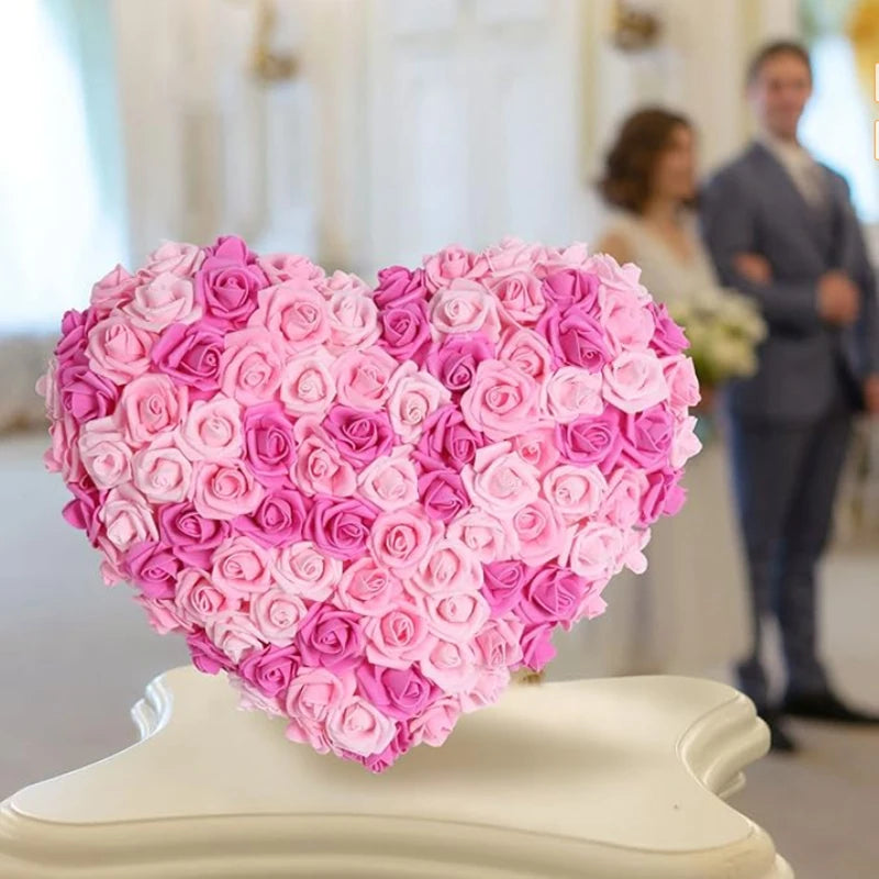 A heart-shaped arrangement of pink and magenta artificial foam roses displayed on a white pedestal.