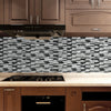 A kitchen backsplash featuring a mosaic of gray and white marble tiles above a wooden countertop.