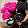 A person is holding a cluster of matte black latex balloons, showcasing them against a dark outfit.