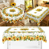 A white tablecloth with a vibrant yellow and green sunflower print is displayed on a dining table.