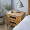 A wooden dresser with drawers and a modern desk lamp on a light wood floor.