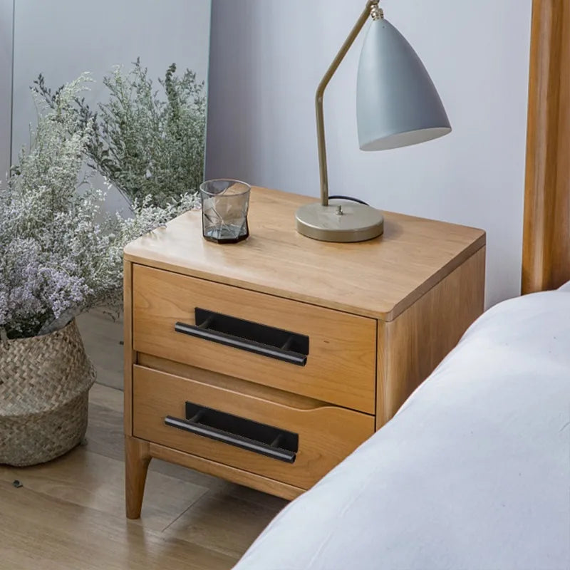A wooden dresser with drawers and a modern desk lamp on a light wood floor.