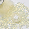 Clear wax sealing beads scattered on a white surface with a round stamp impression in the center.