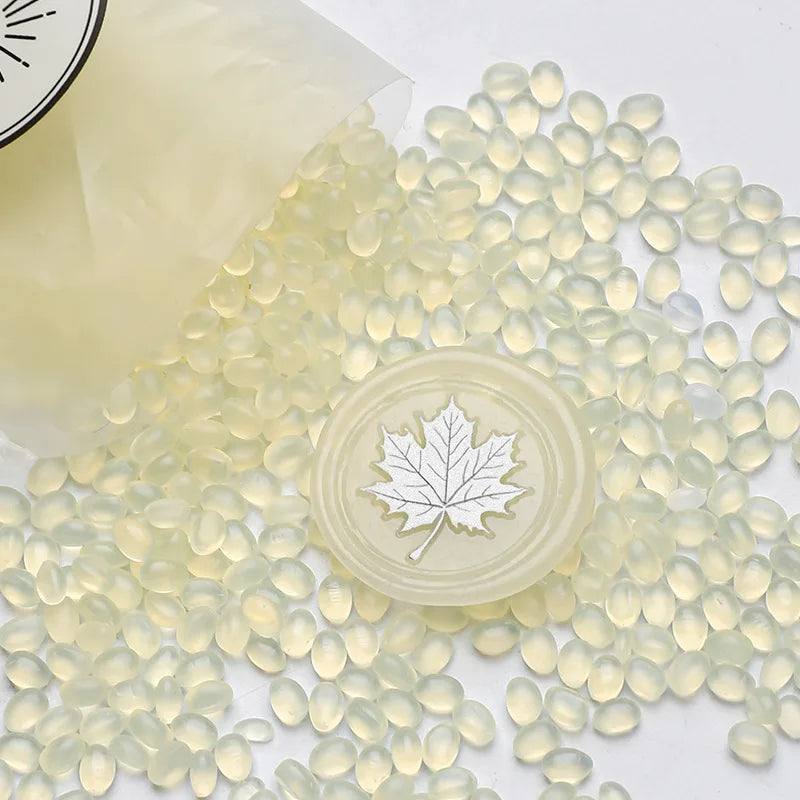 Clear wax sealing beads scattered on a white surface with a round stamp impression in the center.
