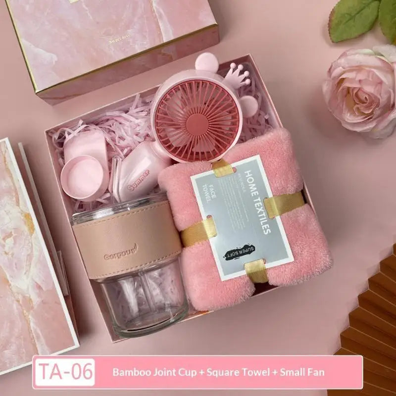 A pink gift set featuring a bamboo joint cup, square towel, and small fan for summer protection.