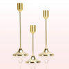 A set of three modern gold metal taper candle holders with slender stems and flared bases.