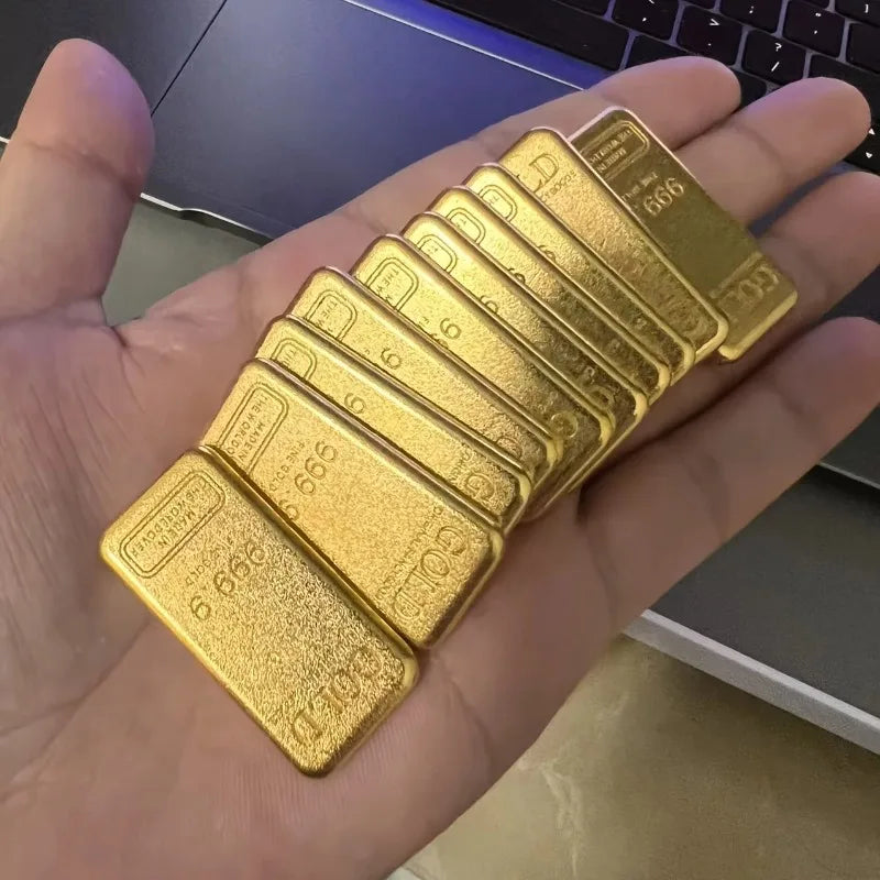 A hand holds a set of ten simulated gold ingot fortune charms stacked together.