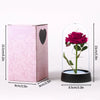 A pink box containing an eternal rose in a glass dome with a black base.