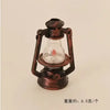 A vintage ceramic miniature lantern with a glass bulb and metal frame for dollhouse décor.