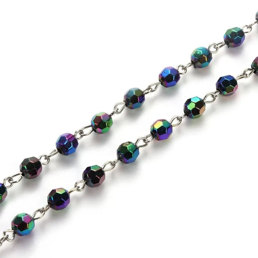 A strand of vintage cross and Virgin Mary pendant rosary necklace featuring iridescent, multi-colored gemstone beads.