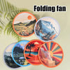 A set of folding fans featuring scenic landscapes and mountains in various colors.
