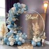 A large arrangement of dusty blue and white latex balloons decorated with dried pampas grass and a gold sign.